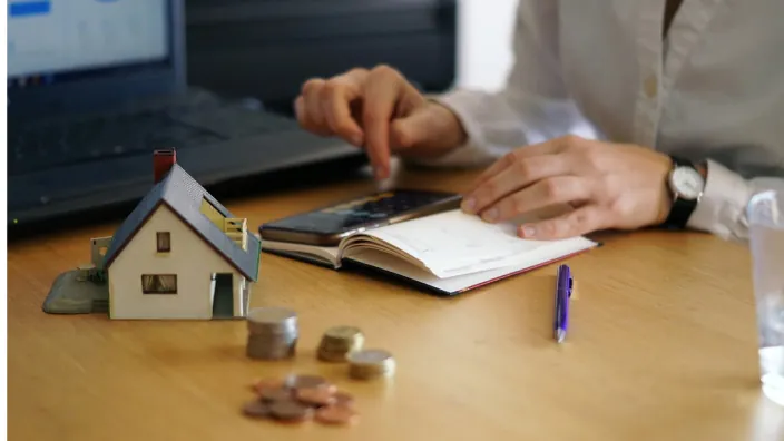 Persona calculando la financiación de una hipoteca para la compra de una casa. Planificación de finanzas y ahorro para una vivienda.